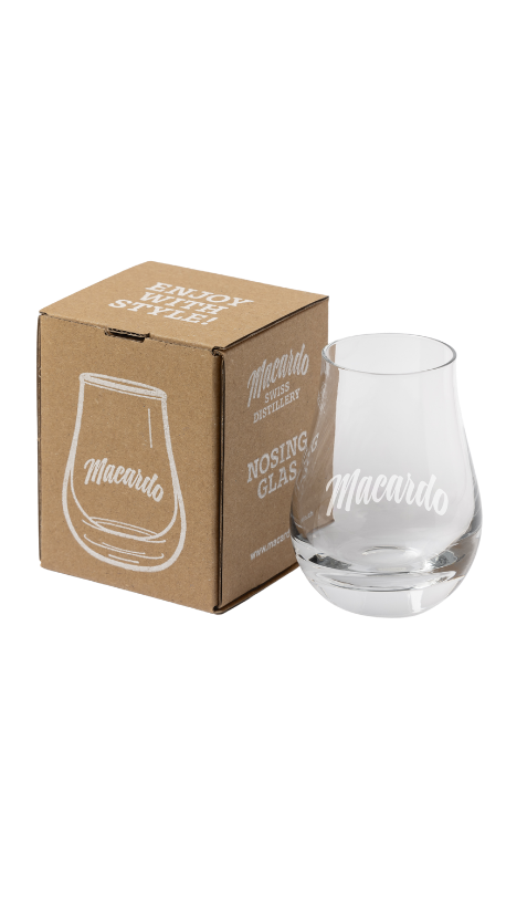 Ein durchsichtiges Nosing Glas mit dem Schriftzug "Macardo" steht neben einem braunen Karton. Auf dem Karton ist ebenfalls ein Glas abgebildet. Beide Objekte sind vor einem weißen Hintergrund positioniert.